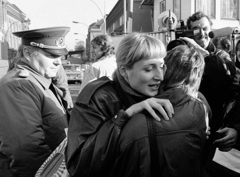 Un ciudadano de Berlin Este abraza a una mujer del Oeste bajo la mirada te un guardia de frontera en el checkpoint de Invalidenstrasse al día siguiente de la caída del Muro