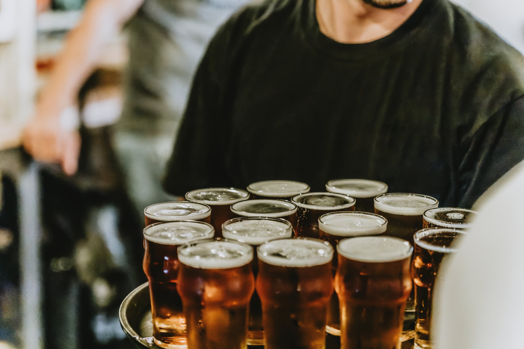 Un camarero con varias cervezas sobre una bandeja.