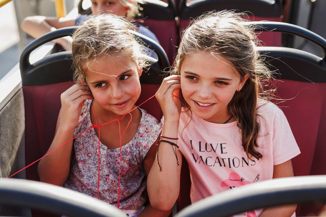 Dos pequeñas disfrutan de su viaje en un bus turístico de City Shightheen