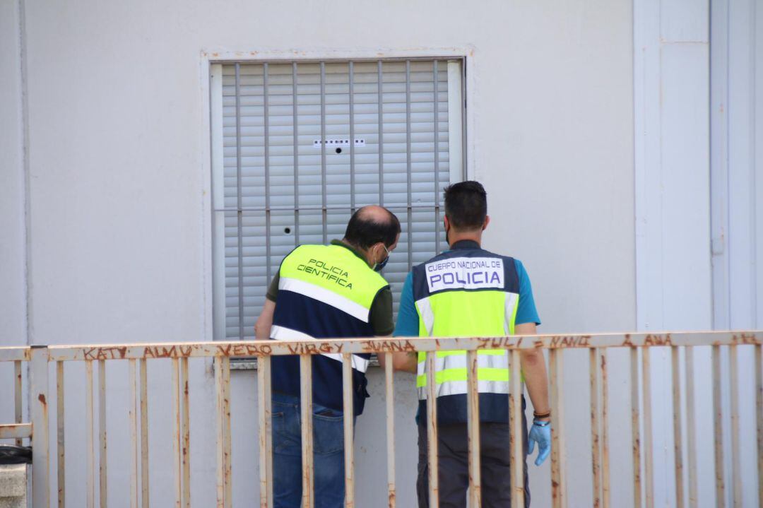 Agentes de la Policía Nacional ante una ventana con impactos de bala en el Polígono Los Cerros 