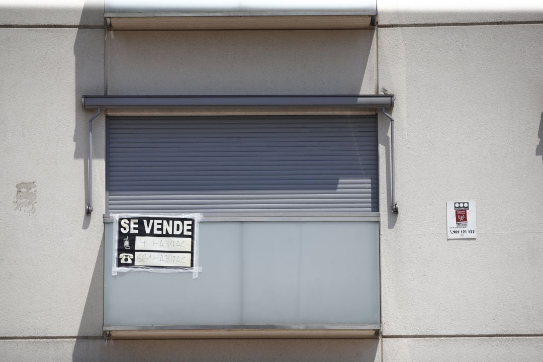 Cartel de &#039;se vende&#039; en el balcón de un piso de un edificio.