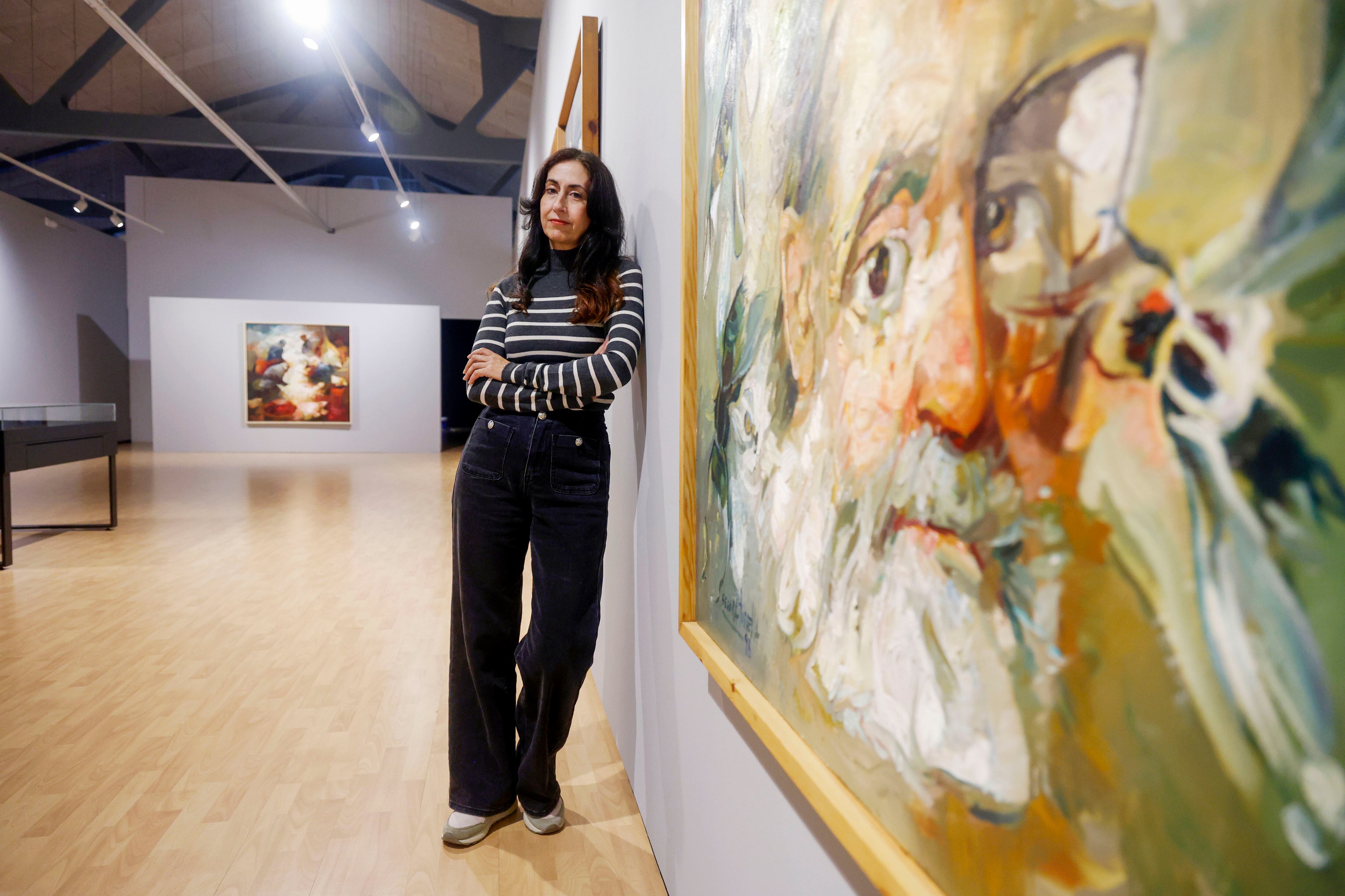 Helena, hija del pintor ferrolés Ricardo Segura Torrella, posa ante obras de su padre que forman parte de la retrospectiva (foto: Kiko Delgado / EFE)