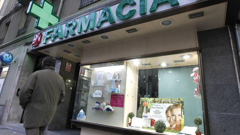 Un viandante pasa junto al escaparate de una farmacia.