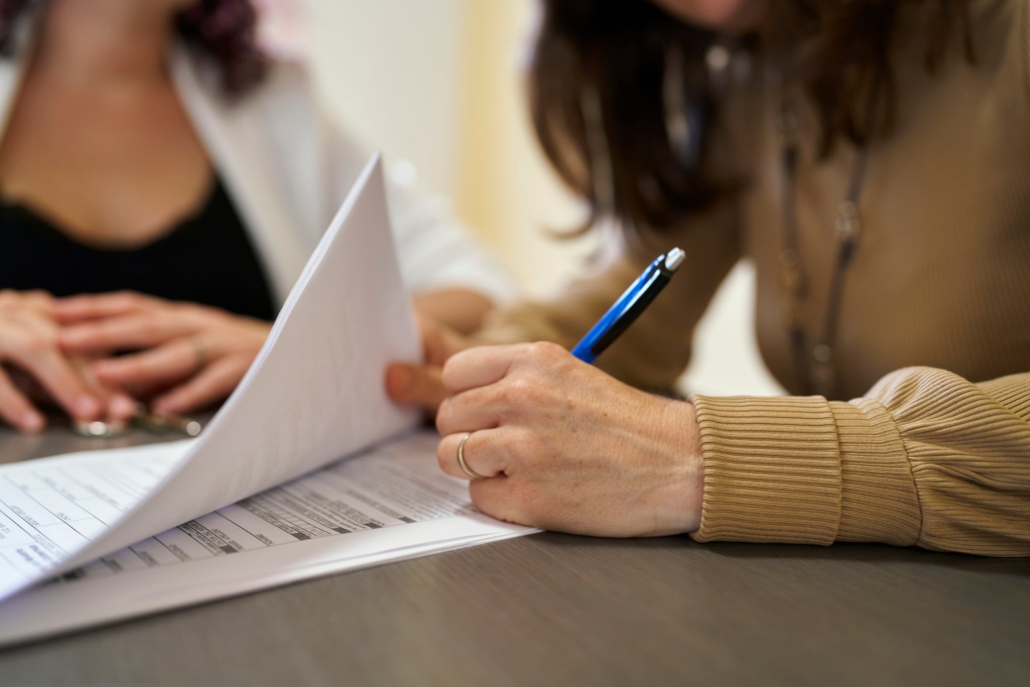 Una mujer firma en un documento.