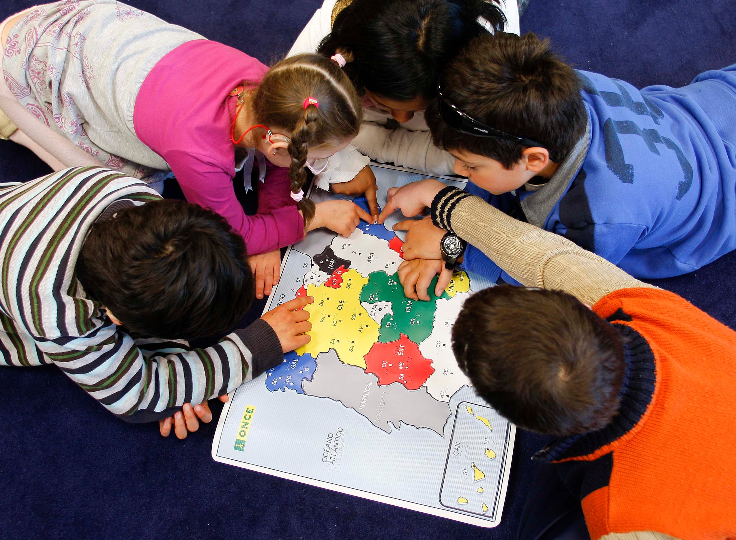 Alumnos del Colegio de la ONCE en Madrid, estudiando el mapa de España en relieve y con títulos en braille.