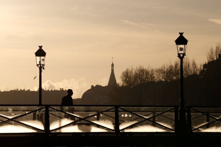 Un hombre pasea por el Puente de las Artes de París. 