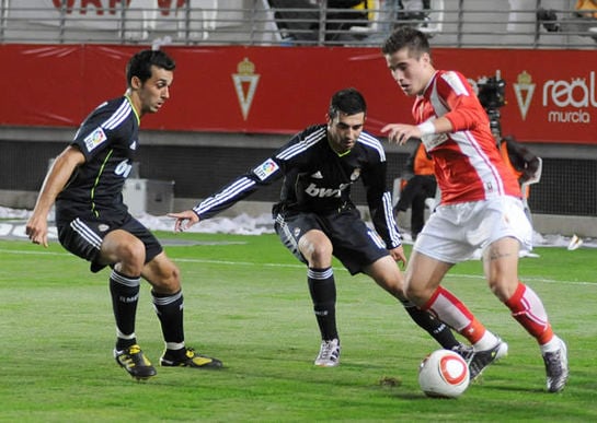 El centrocampista del Real Murcia Daniel Aquino controla el balón entre los defensas del Real Madrid Álvaro Arbeloa y Raúl Albiol