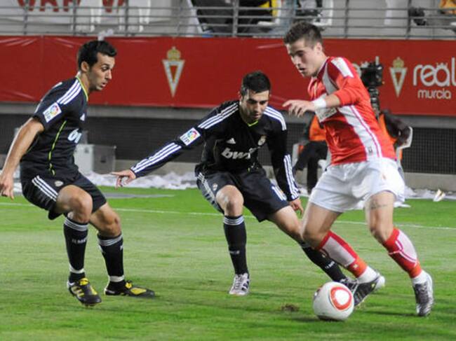 El centrocampista del Real Murcia Daniel Aquino controla el balón entre los defensas del Real Madrid Álvaro Arbeloa y Raúl Albiol