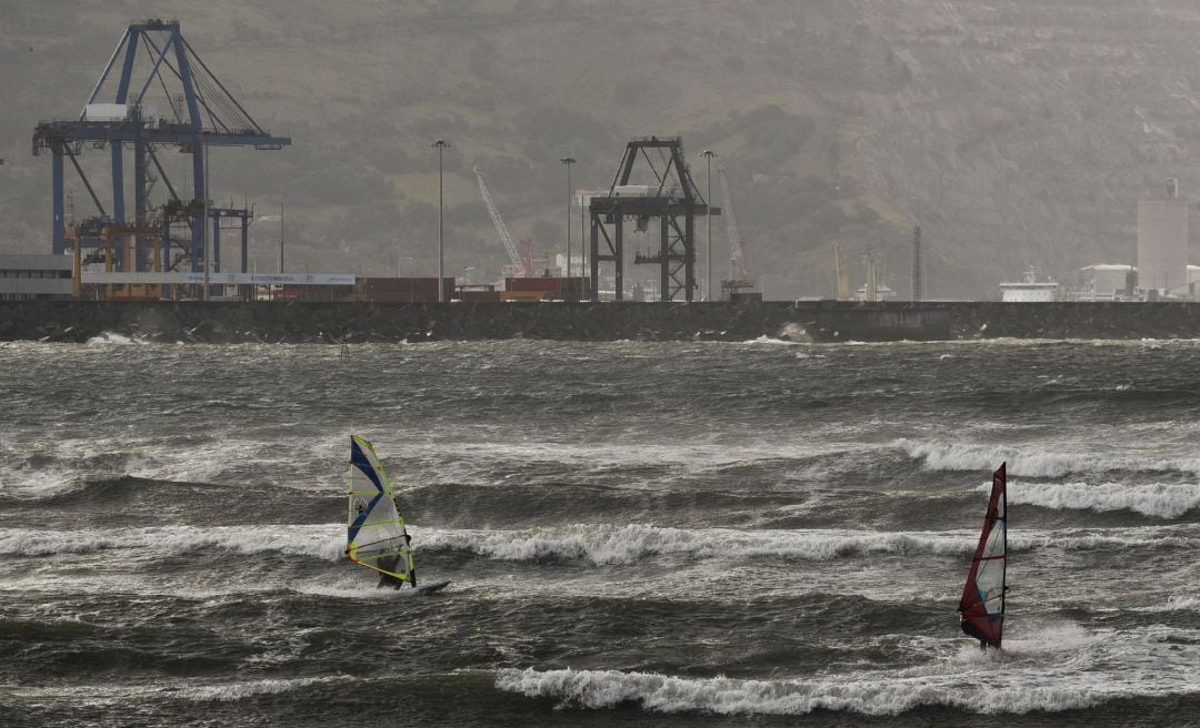 Dos deportistas practican windsurf en la playa de Ereaga en Getxo (Bizkaia), en una jornada marcada por las lluvias y las fuertes rachas de viento en ellitorial cantábrico. 