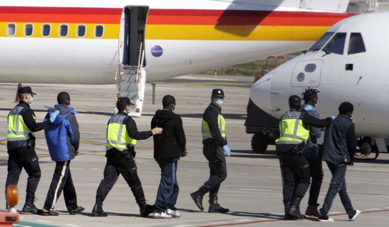 Agentes de la Policía Nacional trasladan hasta el avión a un grupo de inmigrantes desde Melilla un CETI de la Península
