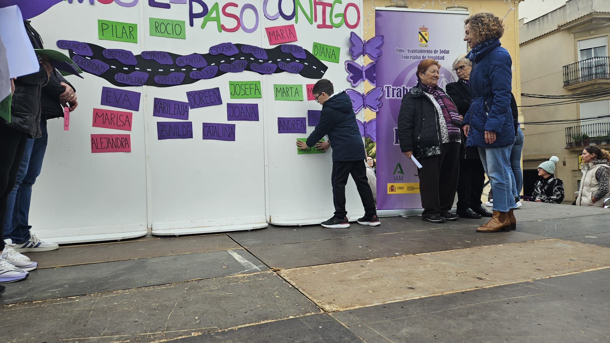 Un niño coloca el nombre de una de las mujeres asesinadas en el mural