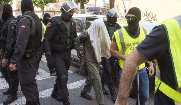 Miembros de la Guardia Civil custodian a uno de los tres hermanos pakistaníes detenidos hoy, en el barrio de Pardinyes de Lleida, por enaltecimiento del terrorismo yihadista a través de internet.