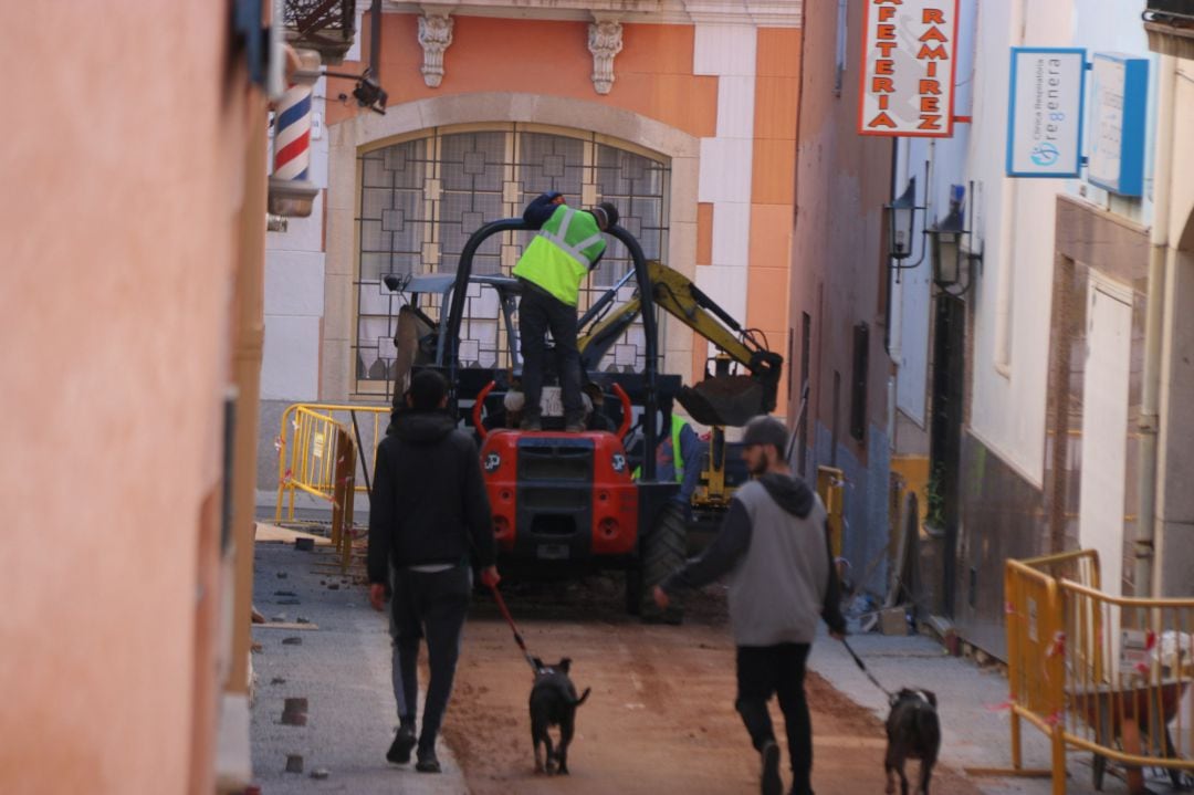 Un carrer amb obres i dos joves passejant els gossos a Palafrugell el passat dijous