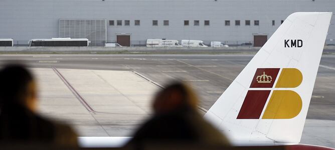 Dos personas ante un avión de Iberia en el aeropuerto de Barajas