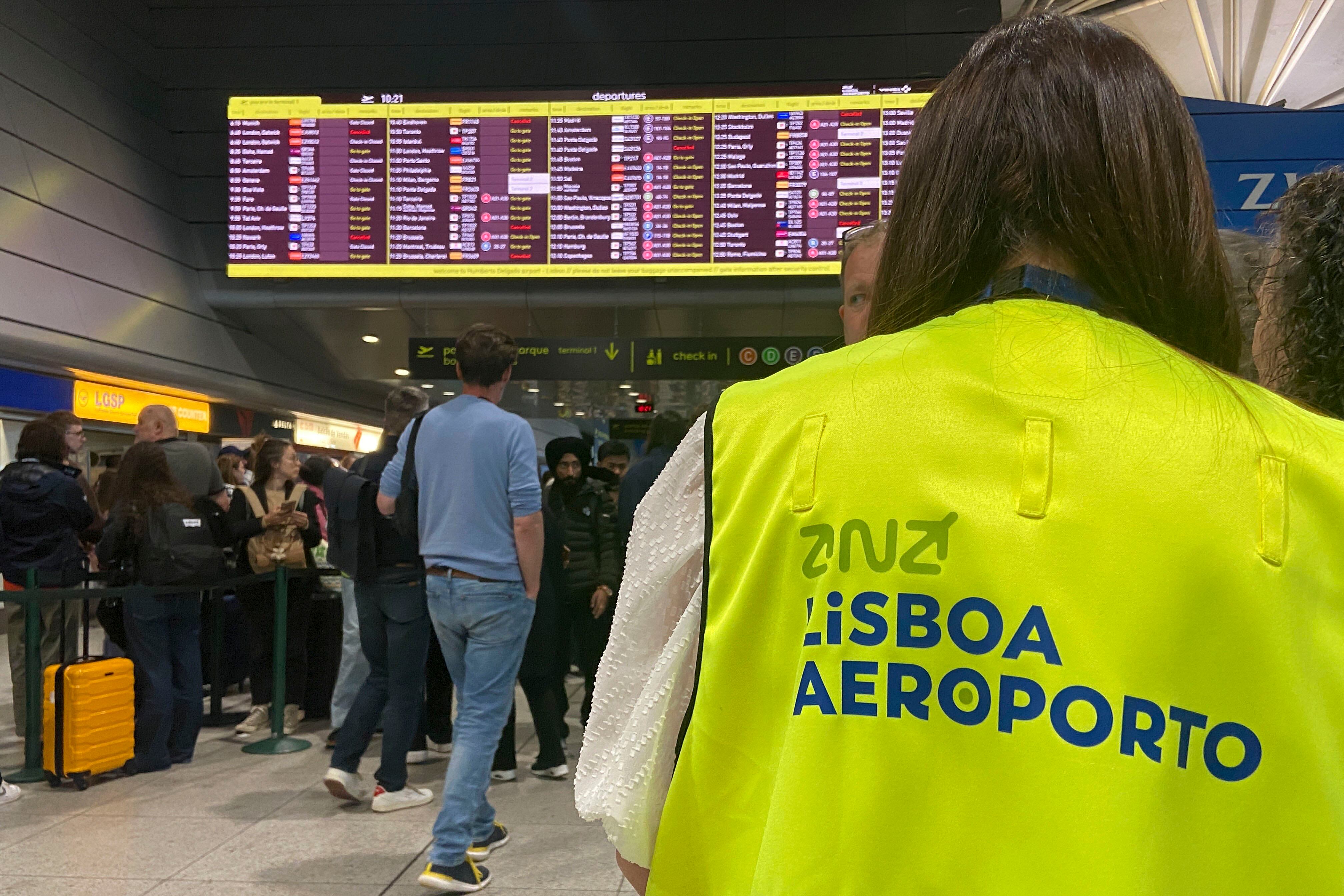 Una trabajadora de la autoridad aeroportuaria portuguesa ANA ayuda a un pasajero en el aeropuerto Humberto Delgado de Lisboa, que este martes retomó la actividad tras un apagón general que este lunes dejó sin electricidad a la Península Ibérica y partes del sur de Francia. 