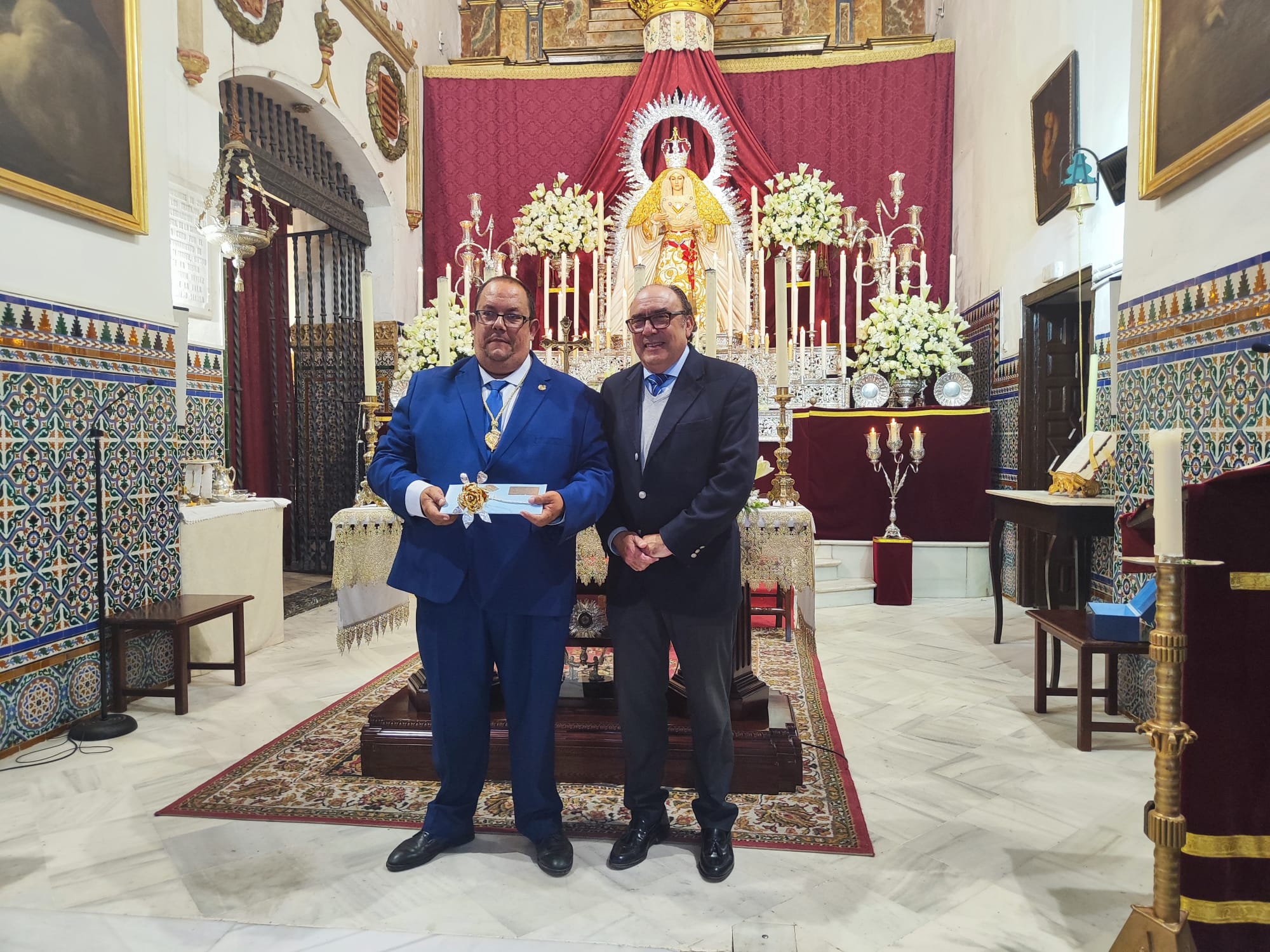 El hermano mayor de la Soledad de Huévar, Manuel Luque, muestra la Rosa de Pasión de Cruz de Guía a los Donantes de Órganos junto al hermano mayor de Los Gitanos, José María Flores