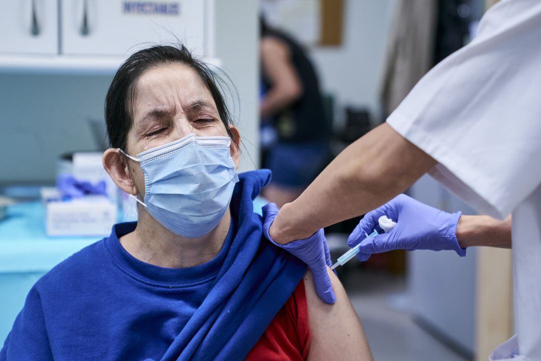 Una sanitaria vacuna a una mujer en el Hogar San Isidro en Madrid este jueves.