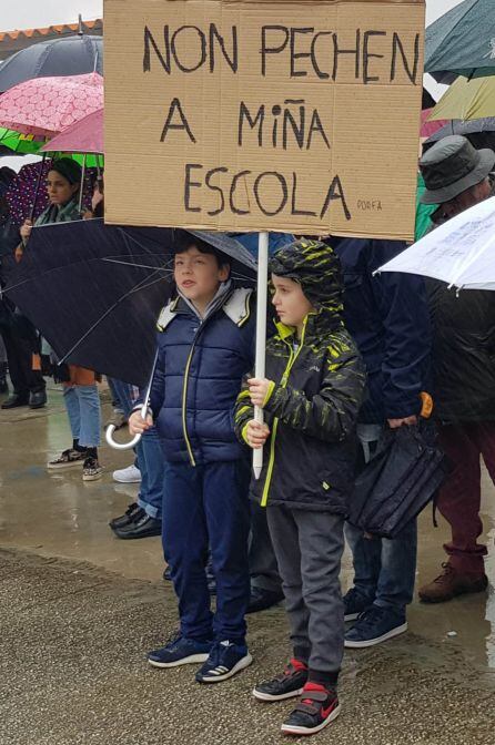 Dos niños sujetan una pancarta contra el cierre de la Escuela unitaria de Sada