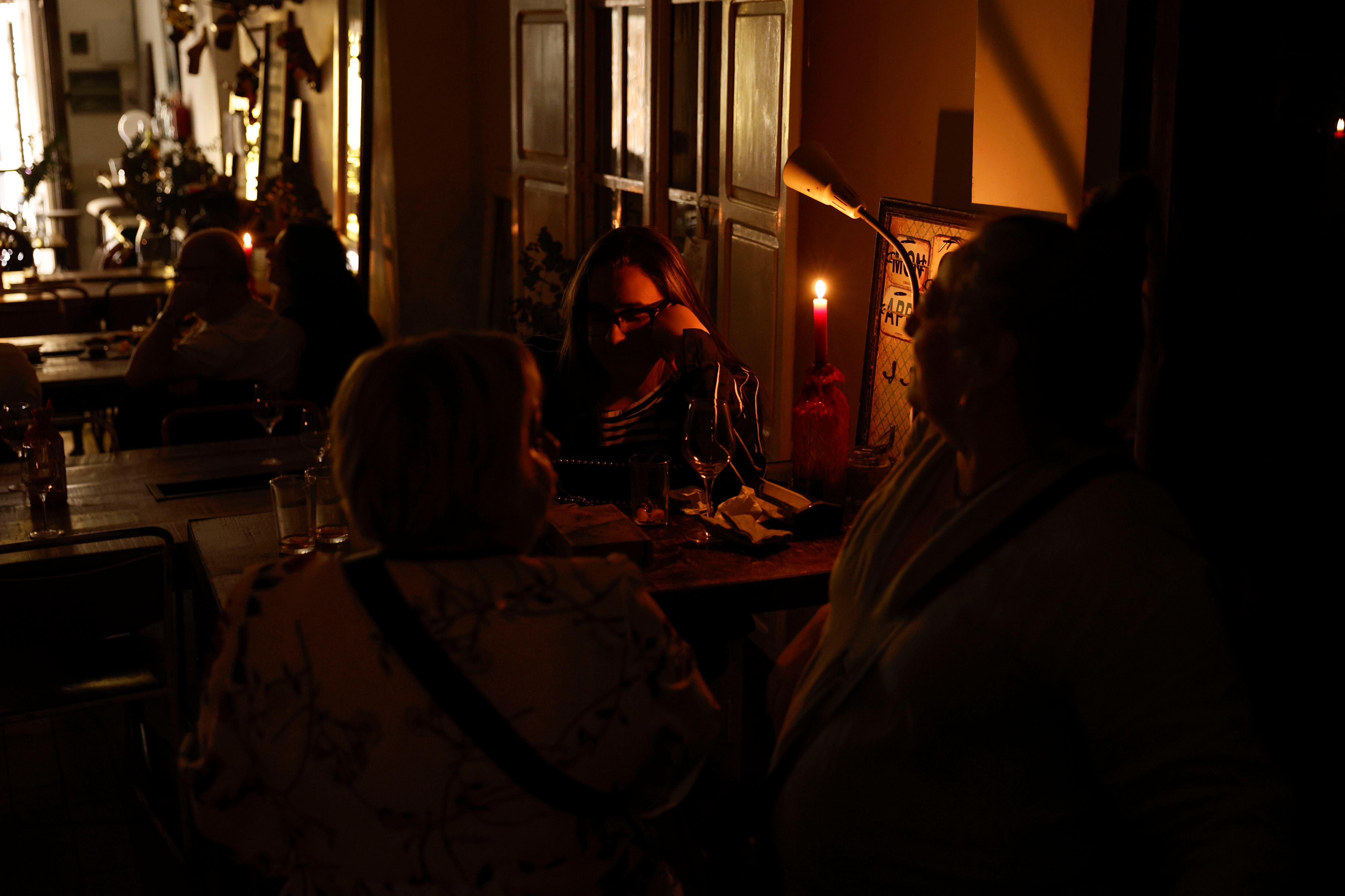 Clientes se alumbran con velas en un restaurante en Valencia este lunes durante el apagón eléctrico.
