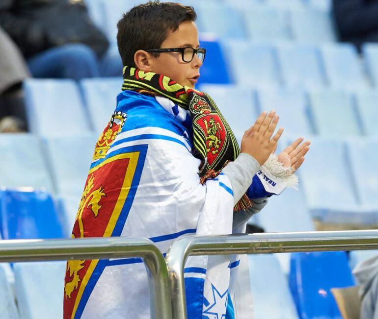 Un joven aficionado del Real Zaragoza aplaude al equipo en un partido en la Romareda