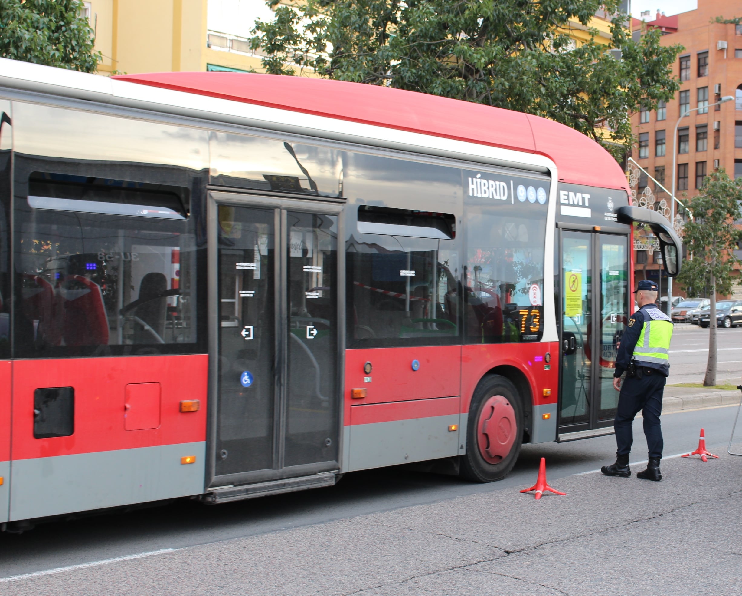 Un agente de policía frente a un autobús de la EMT de València.