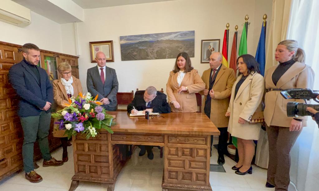 Momento en el que el presidente de la Asociación Cultural &#039;Saudar&#039;, Ildefonso Álcala, firma en el libro de honor, en presencia de alcaldesa, concejales y diputado