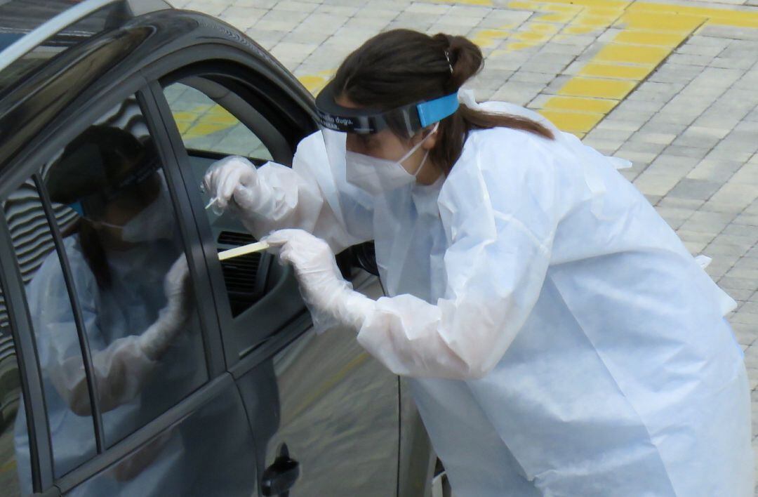 Una trabajadoras del Hospital de Eibar realiza test PCR al conductor de un vehículo en el parking del centro.