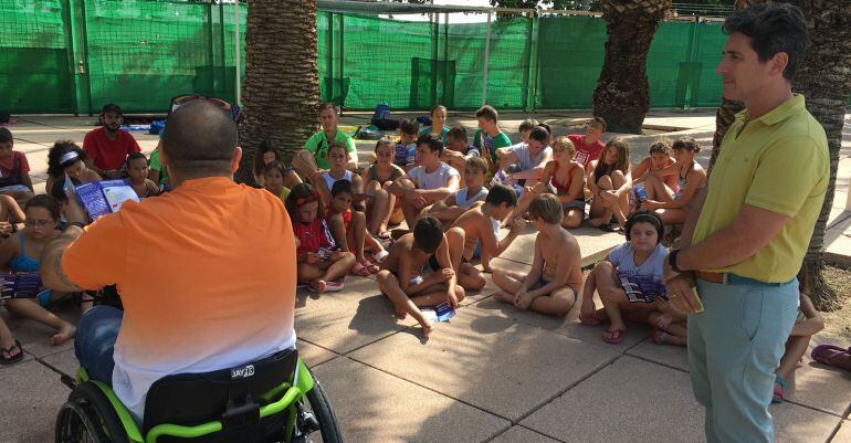 Un miembro de Aspaym habla a niños sobre la importancia de una inmersión segura en el agua