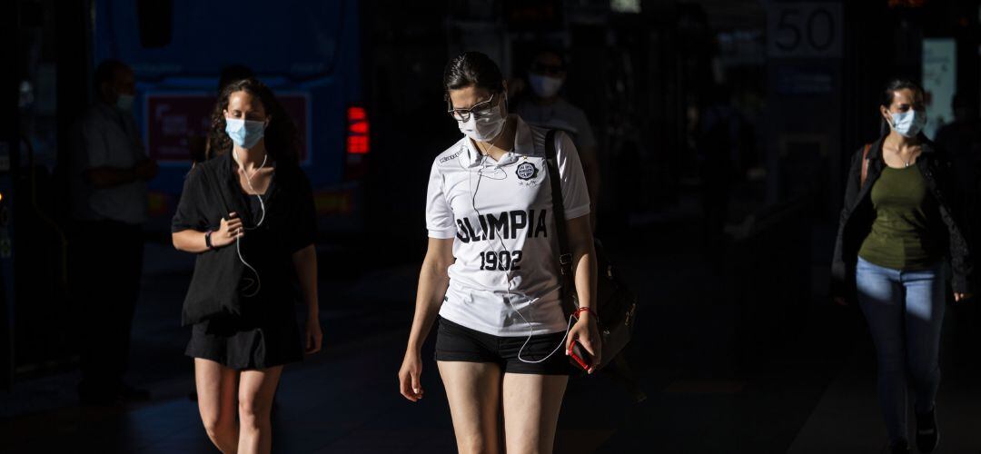 Tres mujeres caminan con mascarilla.