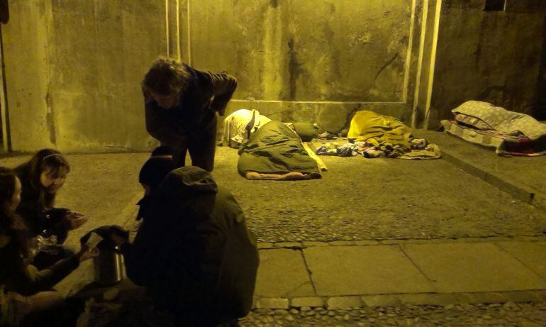 Unos voluntarios preparan café para unos sin techo del centro de Madrid