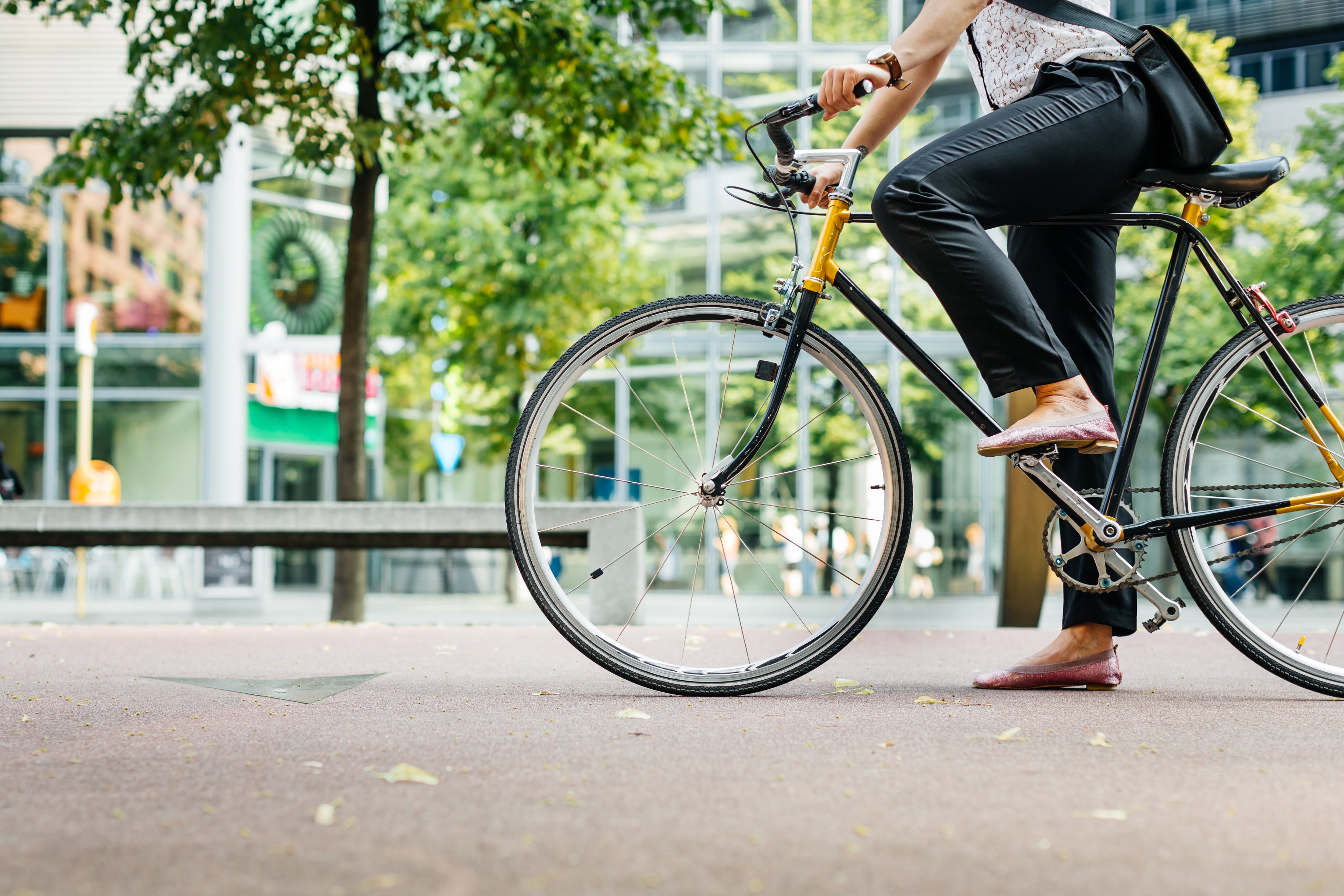 Close up shot of businesswoman&#039;s legs riding a bicycle