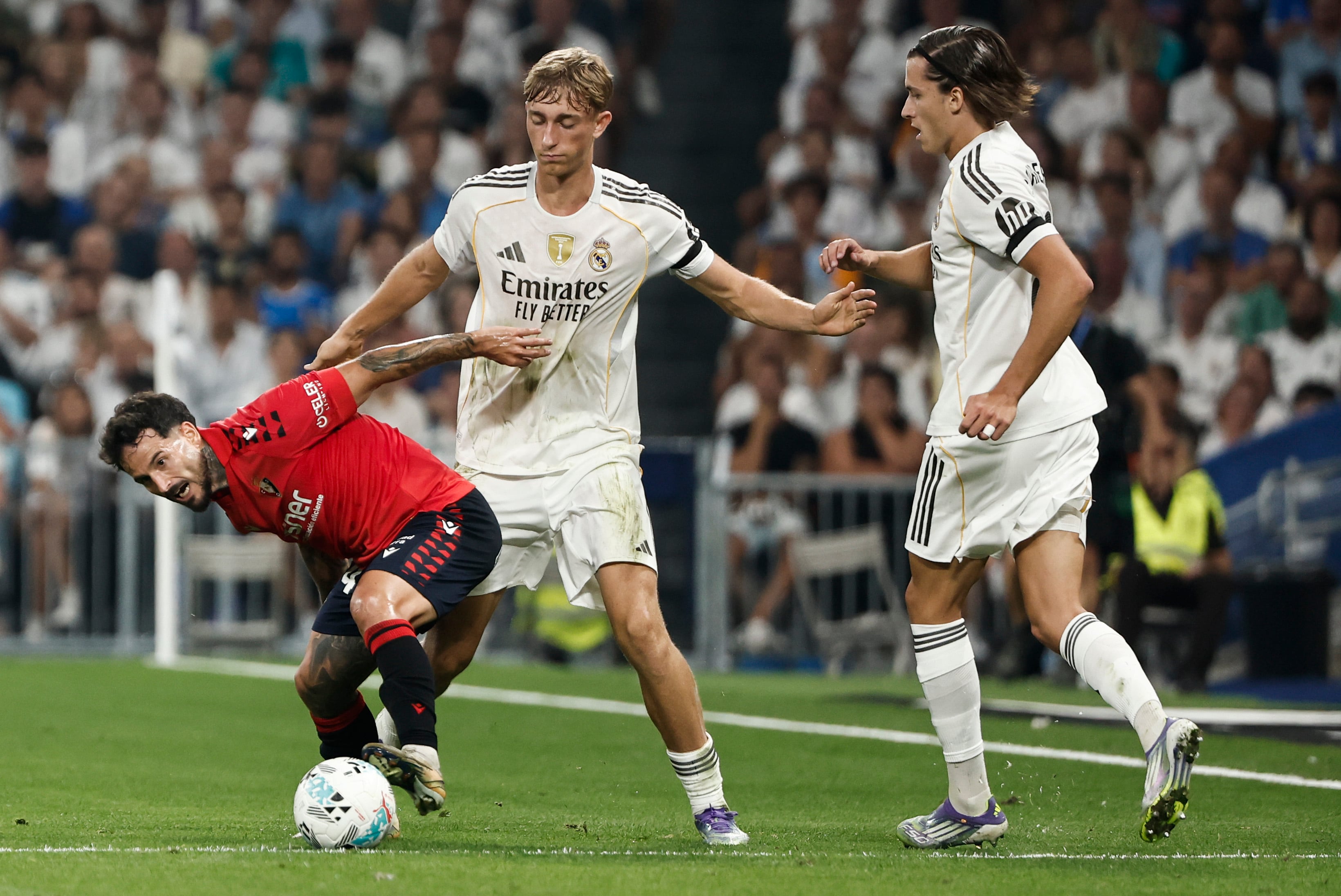 MADRID, 19/08/2025.- El defensa neerlandés del Real Madrid Dean Huijsen (c) lucha con Rubén García (i), de Osasuna, durante el partido de la primera jornada de LaLiga que Real Madrid y Atlético Osasuna disputan hoy martes en el estadio Santiago Bernabéu. EFE/SERGIO PÉREZ
