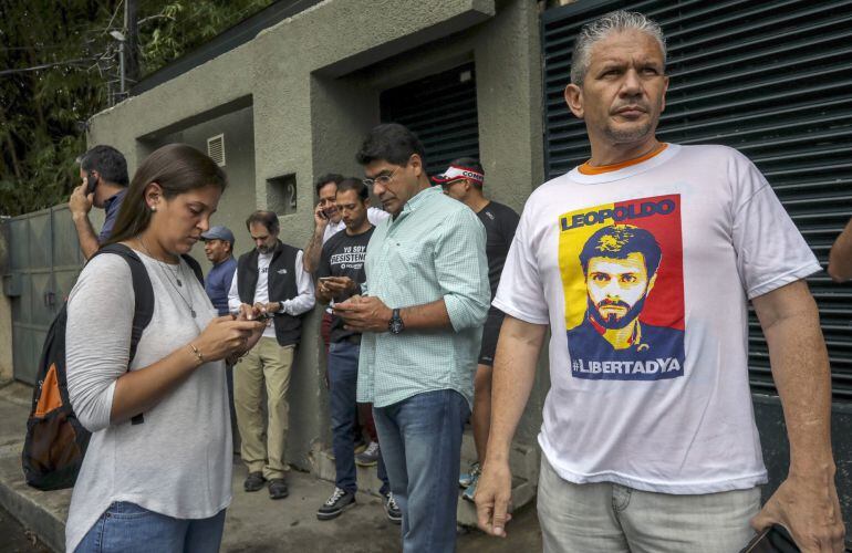 Familiares, militantes del partido Voluntad Popular, junto a miembros del Servicio Bolivariano de Inteligencia Nacional, permanecen en la entrada de la casa en Caracas del opositor venezolano Leopoldo López