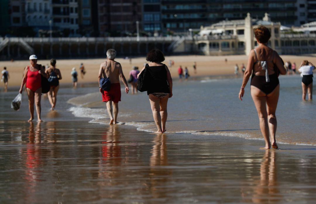 Varias personas pasean por la playa de La Concha.