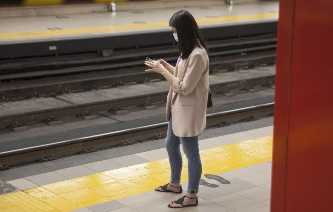 Una mujer utiliza el móvil en el metro.