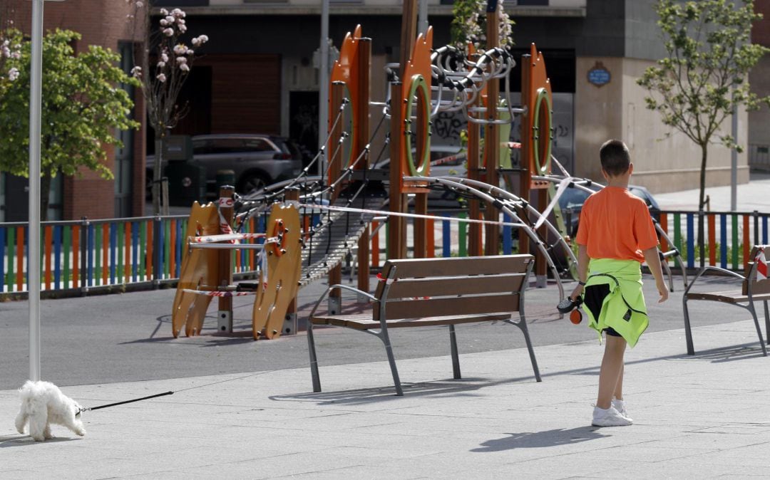 Un niño pasea el perro junto a un parque cerca de su casa este lunes en la capital vizcaína. 