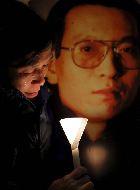 Fotografía de archivo tomada el 12 de enero de 2010 que muestra a una activista llorando junto a una foto del disidente chino Liu Xiaobo durante una vigilia por su liberación en Hong Kong / EFE