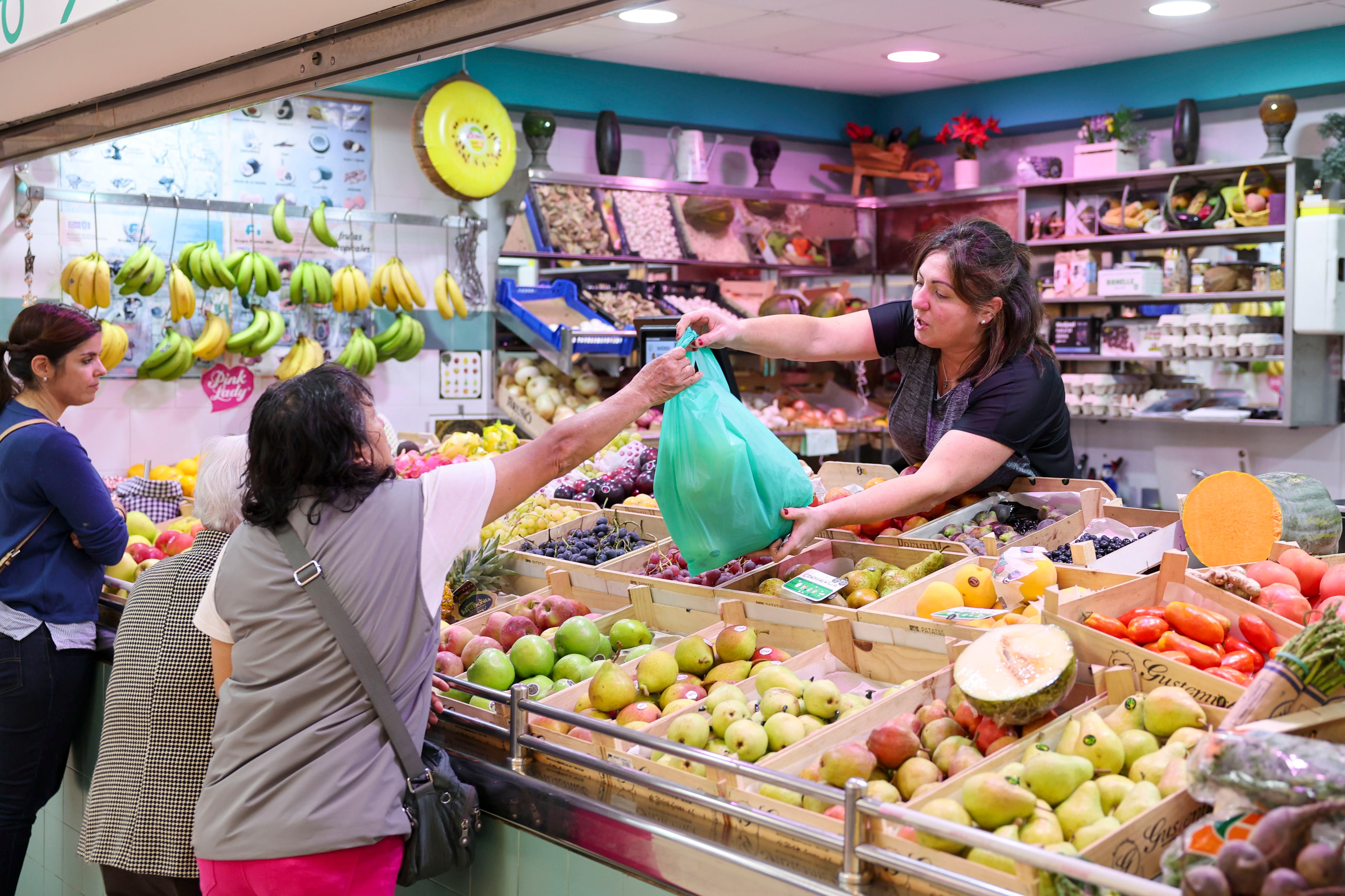 Una tendera atiende a la clientela es una frutería