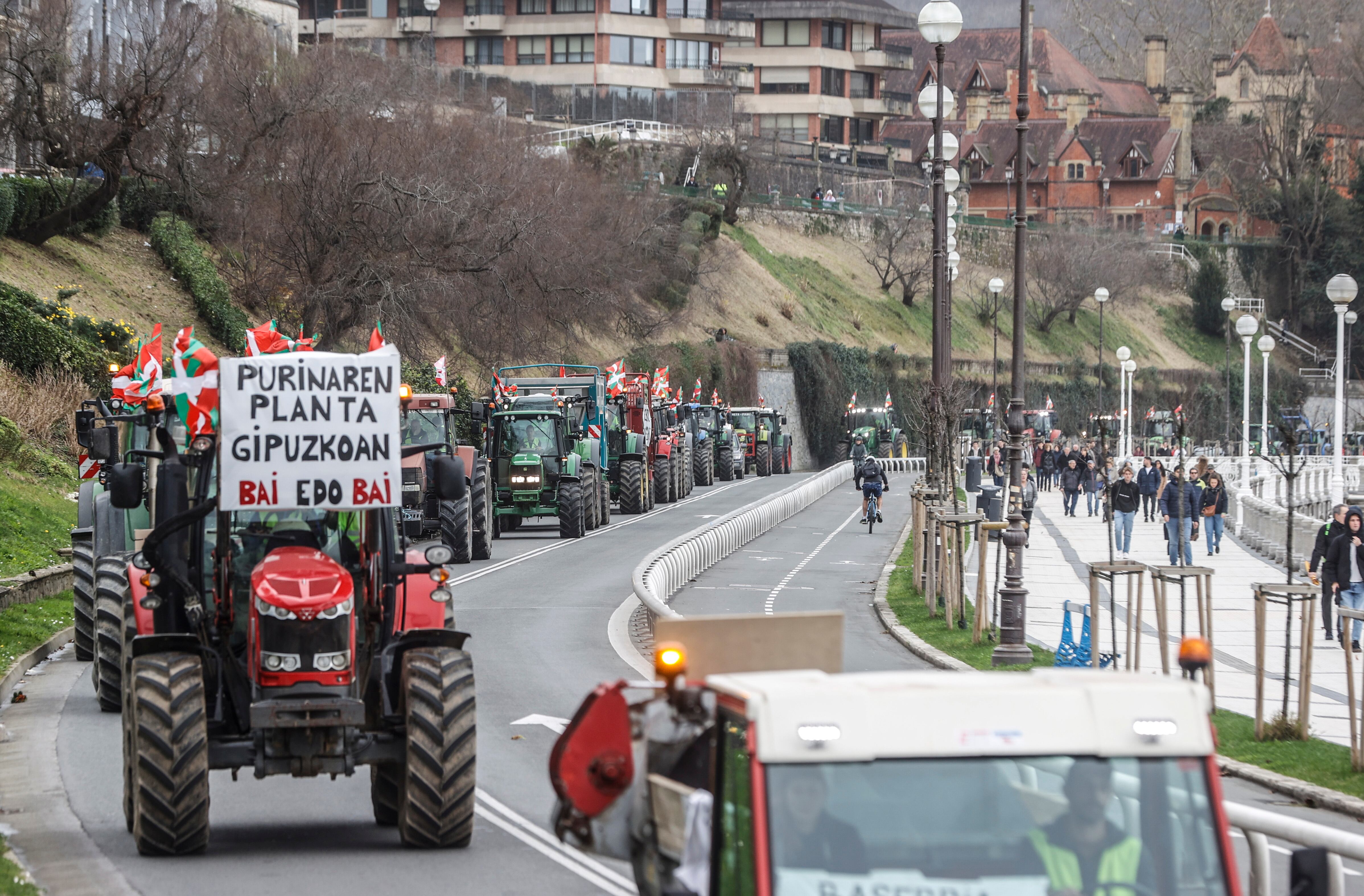 Varias decenas de tractores y otros vehículos rurales pasan por la bahía de la Concha en San Sebastián tras causar este lunes problemas de tráfico en varios puntos de carreteras de Gipuzkoa como la N-I y la N-634, debido las protestas de baserritarras. EFE/Juan Herrero