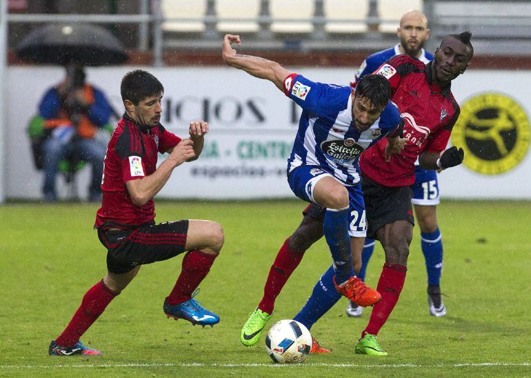 El centrocampista argentino del Deportivo Jonás Gutiérrez (c) lucha por el balón con el defensa Gorka Kijera (i) y el delantero marfileño Lago Júnior (d), del CD Mirandés, durante el partido de ida de octavos de final de la Copa del Rey que se ha jugado e