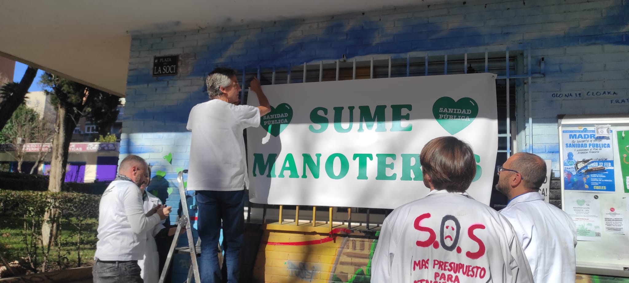 Los médicos del encierro de Manoteras colocan una pancarta en el exterior de los locales de la Asociación de vecinos, La Soci