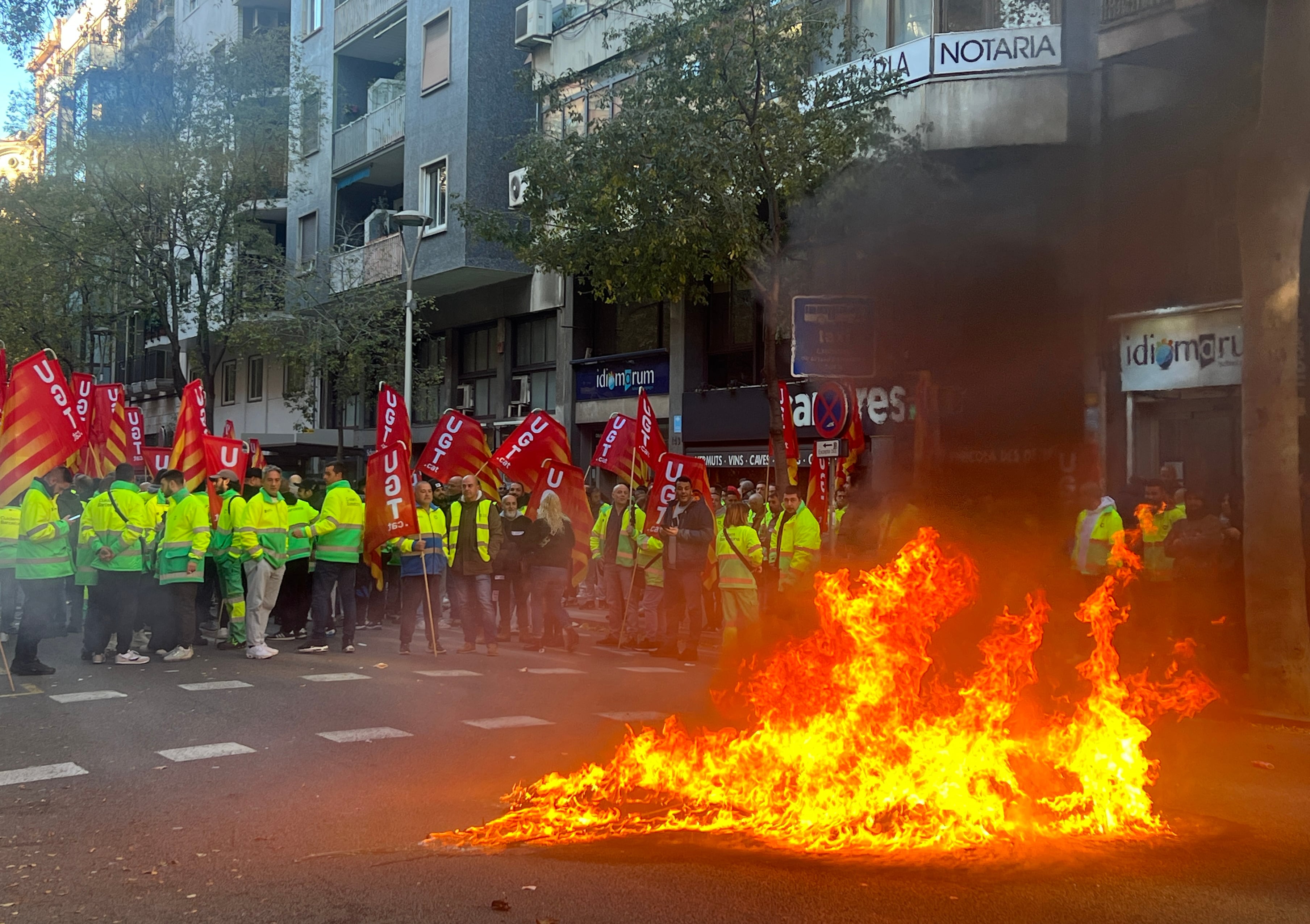 Un contenidor cremant en la protesta dels treballadors de la neteja de Barcelona davant el departament de Treball en el marc de la mediació per la vaga per Nadal.