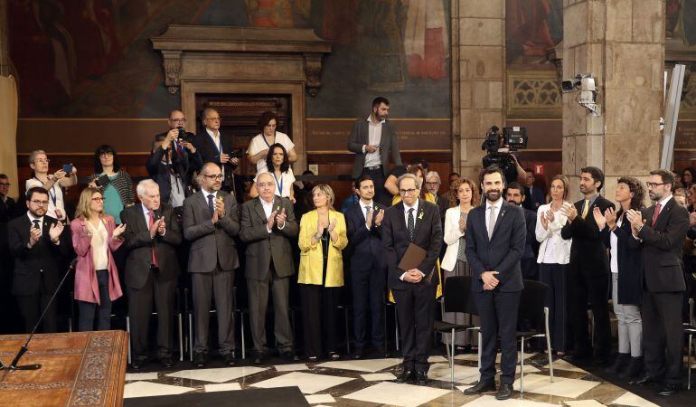 El presidente de la Generalitat, Quim Torra (i), y el del Parlament de Cataluña, Roger Torrent (d), reciben el aplauso de los nuevos consellers del gobierno catalán a su llegada al acto de toma de posesion del nuevo Govern.