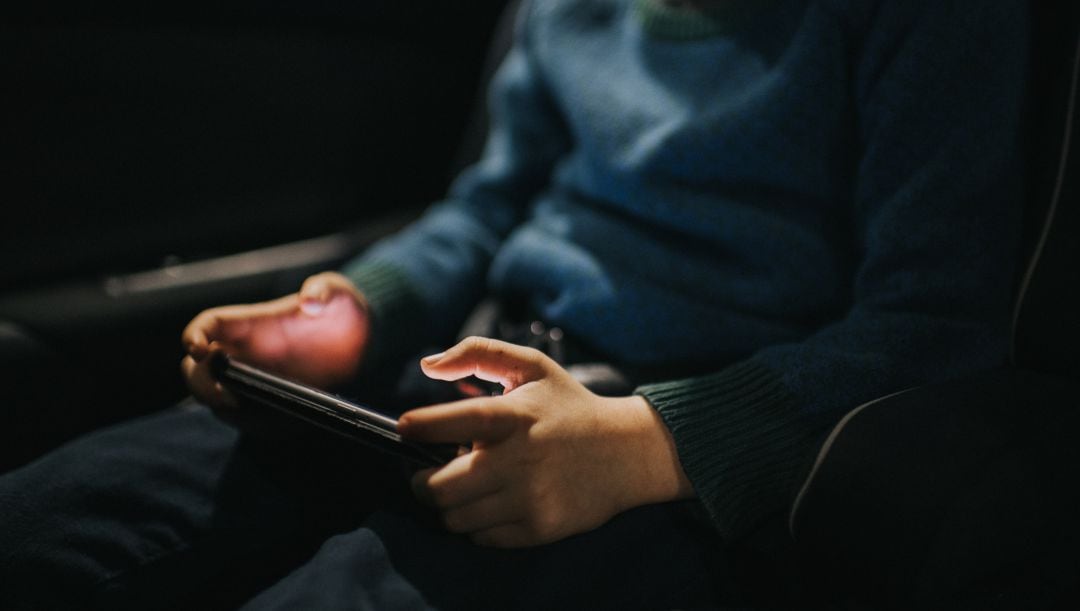 Un niño utiliza un teléfono móvil en el coche. 