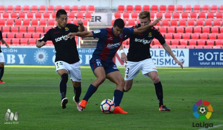 Delgado i Mossa intenten robar la pilota a un rival del Huesca.