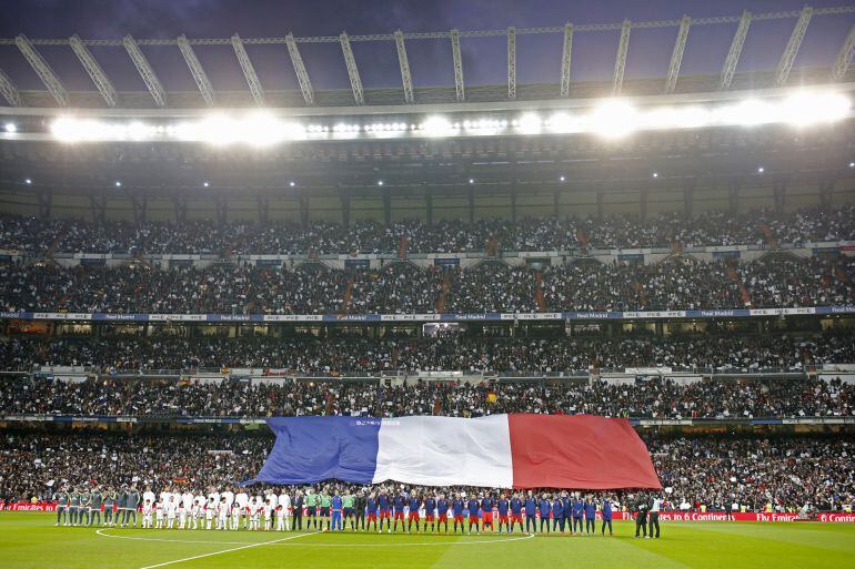 La bandera francesa en un lateral del Bernabéu mientras las plantillas de Real Madrid y Barcelona escuchan La Marsellesa