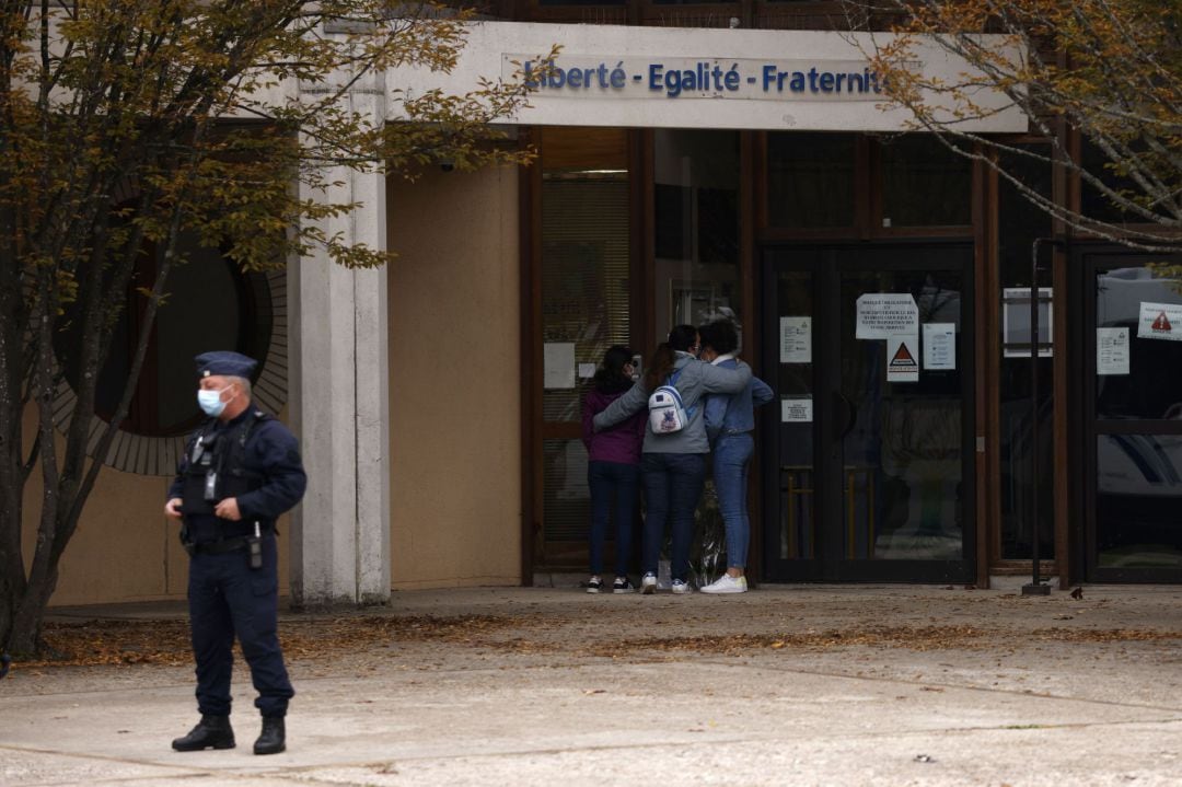 Adolescentes depositan flores frente a la escuela secundaria Bois d&#039;Aulne para presentar sus respetos después del asesinato de un maestro en Conflans Saint-Honorine, en las afueras de París.