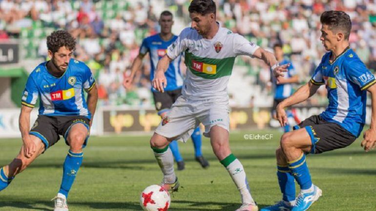 El jugador del Elche Javi Flores controla el balón ante dos adversarios
