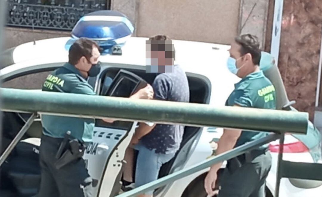 Dos guardias civiles introducen al detenido en una unidad móvil.