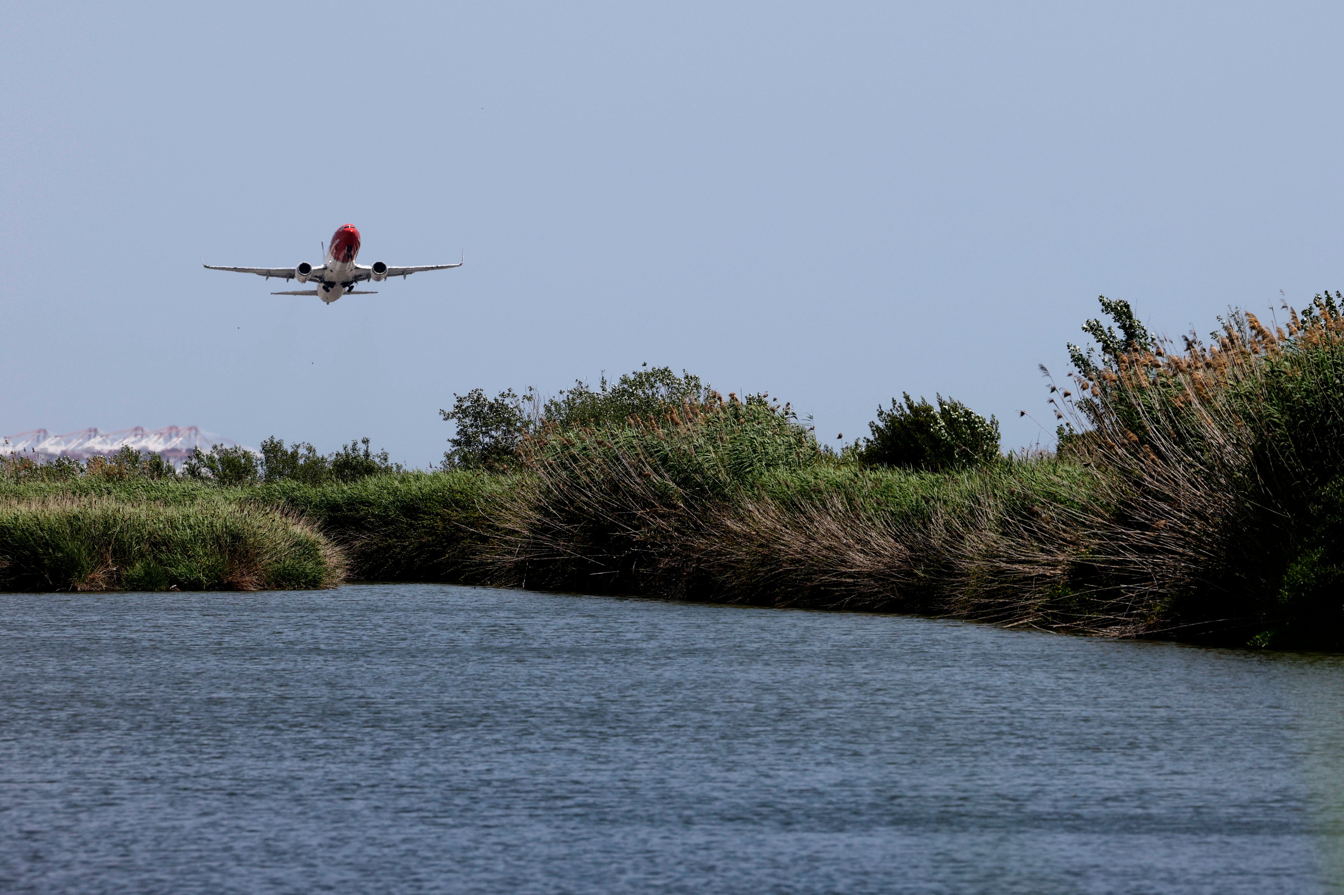 GRAFCAT9271. EL PRAT (BARCELONA), 10/06/2025.- Un avión despega del Aeropuerto de Barcelona-El Prat sobrevolando la laguna de El Remolar este martes, después de que el presidente catalán, Salvador Illa, haya anunciado que Aena invertirá 3.200 millones en la ampliación del Aeropuerto Josep Tarradellas Barcelona-El Prat, un proyecto que contempla extender la tercera pista, la más cercana al mar, en 500 metros. EFE/Alberto Estévez